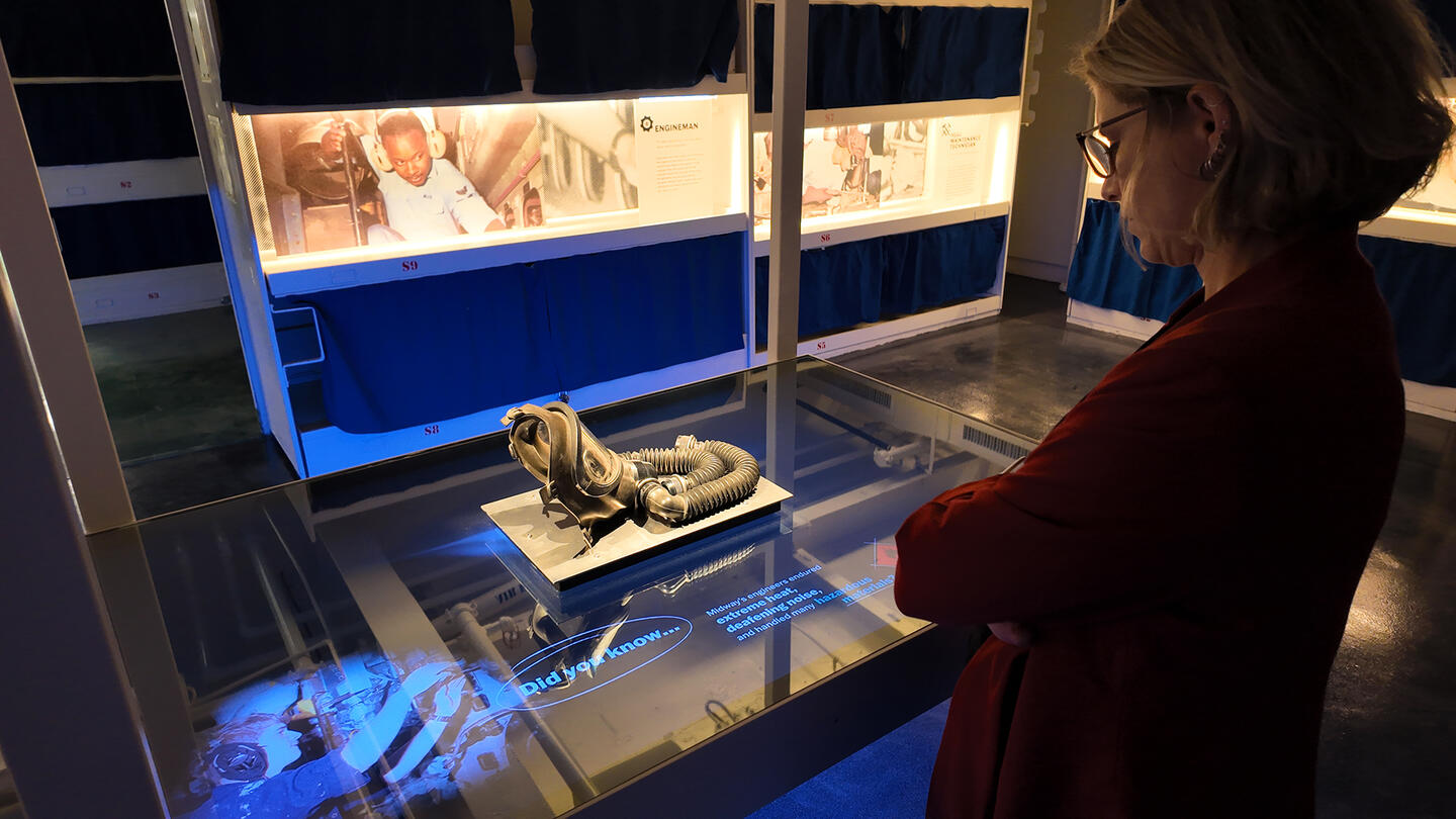 Woman looking at an engineering artifact at the USS Midway exhibition