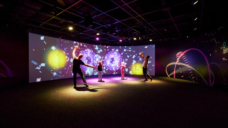 Photo of parents and children dancing in front of a large project at the Sydney Opera House