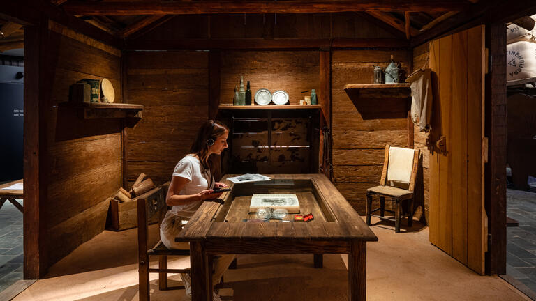 Image of a woman sitting at a table in an exhibit at the stockman's hall of fame.  
