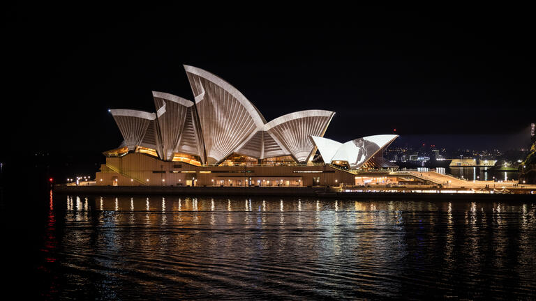 The Sydney Opera House at night, with projection mapping across its sails. Photography by Daniel Boud