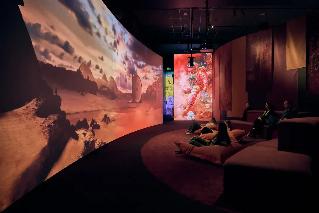People sit on beanbags in low-lit space watching large screen